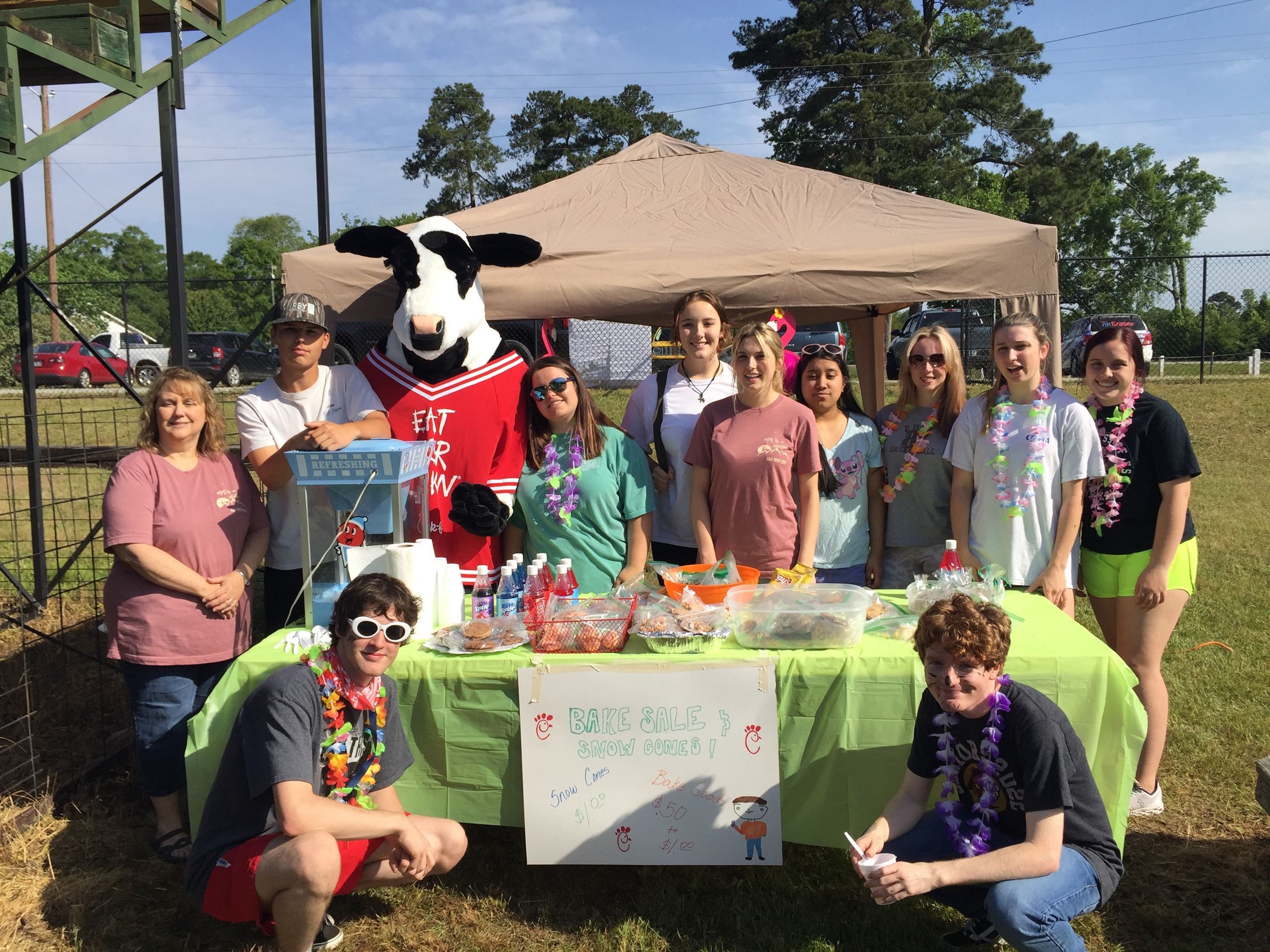 People and the Chick-fil-a cow standing in front of a tent