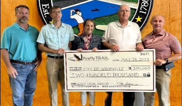 Five people standing and holding a large check for $200,000