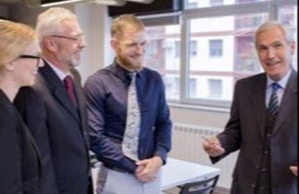 Four adults standing in a conference room. 
