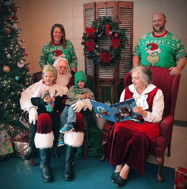 Mrs. Santa reading to Santa, two children and two adults. 