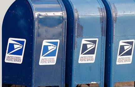 Three blue United States mailboxes in a line.  