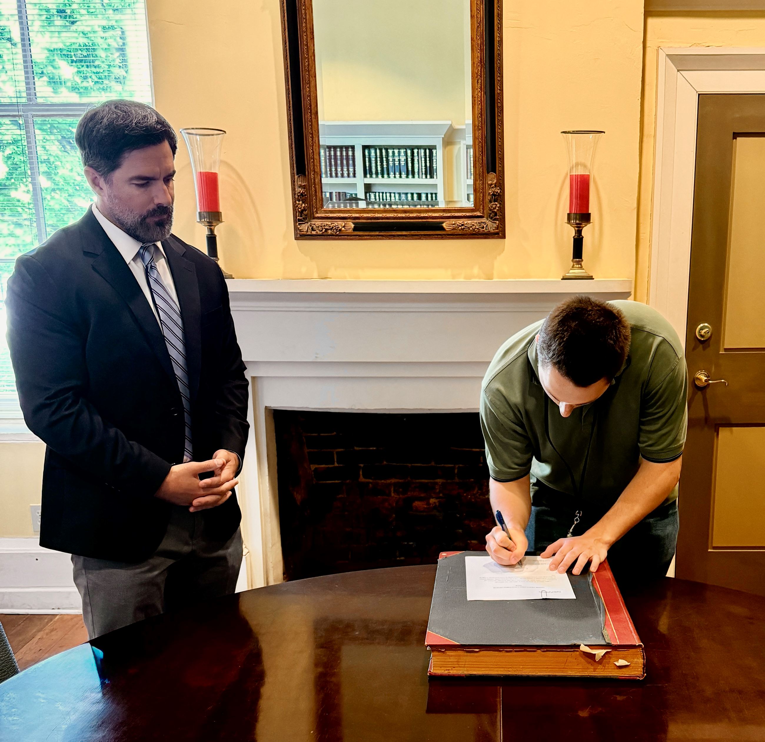 Jaden Atkinson signs oath while Judge Wall looks on